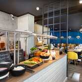 A stylish breakfast buffet with fresh fruits, vegetables, and yogurt is set up in a modern dining area with vibrant blue walls.