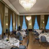 A luxurious banquet hall features elegantly set tables under grand chandeliers, creating a sophisticated atmosphere.