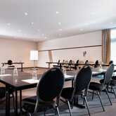 An empty conference room is set up with arranged tables and chairs, ready for a business meeting.