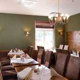 Ein elegantes Restaurant mit grünen Wänden, festlich gedeckten Tischen und modernen Kronleuchtern lädt zum Verweilen ein.