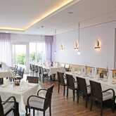 Elegant dining tables are set with white linens and glassware in a bright, modern restaurant interior named Vineta.