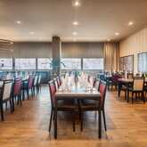 The elegant restaurant dining area features neatly arranged tables with red and beige chairs under modern circular lights.