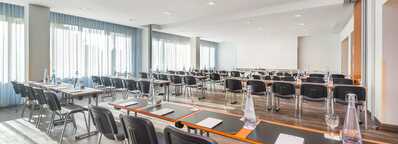 A well-lit classroom at Wittenberg School is set for a seminar with neatly arranged tables, chairs, and bottled water.