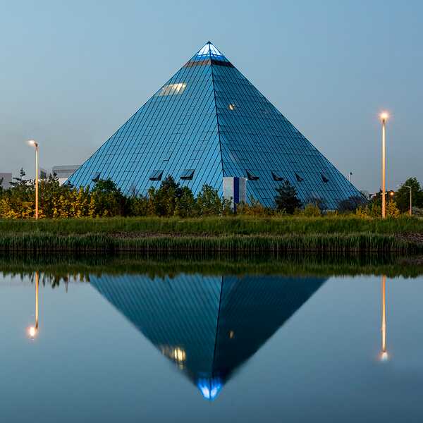 Das Excelsior Hotel Nürnberg Fürth beeindruckt mit seiner pyramidenförmigen Glasfassade, die sich im Wasser spiegelt.