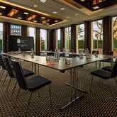 A modern meeting room setup at the Wasserturm hotel with a large table and chairs, surrounded by floor-to-ceiling windows.