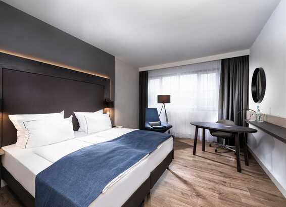 Ein elegantes Executive-Zimmer mit großem Bett, modernem Schreibtisch und gemütlicher Beleuchtung lädt zum Entspannen ein.