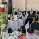 Elegant tables set for a festivity feature tall vases with red roses, creating a sophisticated ambiance.