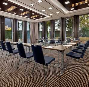 A modern meeting room features U-shaped tables and elegant blue chairs, creating an inviting space for discussions.