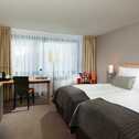 A modern twin bed room features sleek decor, a work desk, and a flat-screen TV, creating a cozy and functional space.