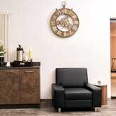 Eine elegante Lobby mit schwarzem Sessel, Wanduhr und Kaffeestation auf einem braunen Schrank.