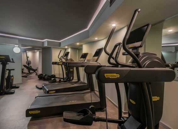 A modern gym features treadmills and exercise bikes lined up in a sleek, well-lit room.
