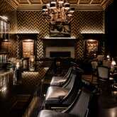 Luxuriöse Bar mit gepolsterten Ledersesseln, kunstvoller Decke und schimmerndem Kronleuchter schafft eine elegante Atmosphäre.