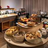 Einladendes Frühstücksbuffet im Best Western Hotel Achim Bremen mit einer Auswahl an frischen Brötchen und Broten in Körben, Obst wie Äpfeln, verschiedenen Gebäckstücken, einem Toaster und diversen Aufstrichen und Cerealien im Hintergrund.