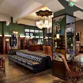 A stylish hotel lobby bar features elegant decor, a long leather sofa, and vintage accents under soft ambient lighting.