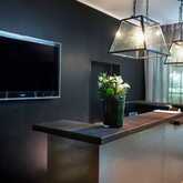 A modern reception counter features elegant pendant lights, a bouquet of flowers, and a wall-mounted TV in a sophisticated setting.