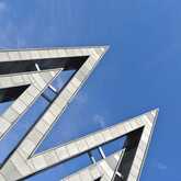 Moderne Architektur mit spitzen Winkeln und Metallstrukturen vor klarem, blauem Himmel bei der Messe Leipzig.