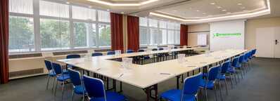 Ein heller Konferenzraum mit blauen Stühlen und einem langen Tisch, vorbereitet für ein Meeting im Ehrenbreitstein-Stil.