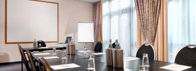 A modern conference room is set up for a meeting with notepads, water bottles, and glasses on a large table.