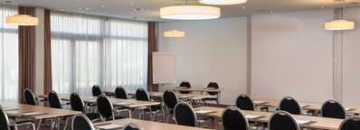 A well-lit meeting room, set up classroom-style with rows of tables and chairs, awaits attendees in Jupiter I.