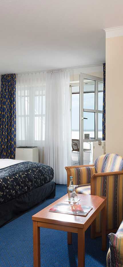 A cozy hotel room features a double bed, a striped sofa, and a coffee machine, creating a comfortable business environment.