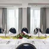A beautifully decorated banquet room features an elegant table setting with candles, floral arrangements, and neatly folded napkins.