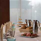 A festive table is elegantly set with baskets of bread, plates of sliced meat, and polished silverware for a celebration.
