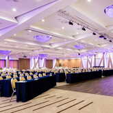 A spacious conference room with elegant lighting and neatly arranged tables and chairs, ready for a high-profile event.