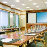 A conference room is set up for a meeting with neatly arranged chairs, tables, and water bottles.
