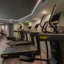 Ein moderner Fitnessraum mit Laufbändern und anderen Trainingsgeräten unter stimmungsvoller Beleuchtung.