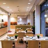A neatly arranged breakfast room with wooden tables, set with dishes and cups, adjacent to a modern buffet area.