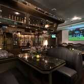 A cozy bistro bar features plush seating, a well-stocked counter, and a large screen displaying a soccer match.