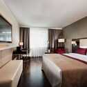 Ein elegantes Hotelzimmer mit einem großen Bett, einem Schreibtisch und einem Flachbildfernseher an der Wand.