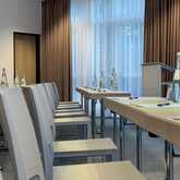 A conference room is set up with rows of chairs, tables, water bottles, and pens, ready for a meeting.