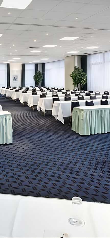 Ein großer Konferenzraum in Düsseldorf ist mit Tischen, Stühlen und einem Rednerpult für eine Veranstaltung vorbereitet.