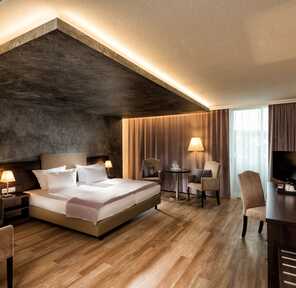 Ein Deluxe-Zimmer mit einem großen Bett, elegantem Holzboden und stilvoller Beleuchtung schafft eine luxuriöse Atmosphäre.