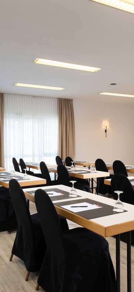 A well-lit meeting room with neatly arranged tables and chairs, ready for a conference in Wendelstein.