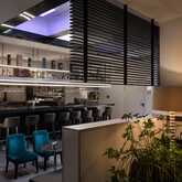 A modern hotel bar features sleek seating, ambient lighting, and a stylish counter with an array of bottles and glasses.