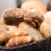 A basket brimming with assorted breads and croissants showcases a delicious breakfast detail.