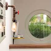 A rustic light bulb fixture illuminates the lobby, with a round window offering a view of greenery outside.
