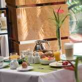 A beautifully set breakfast table features coffee, juice, an egg, pastries, and fresh fruit on a sunny morning.
