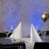 Elegant table setting with folded napkins, wine glasses, and a decorative candle in a stylish restaurant ambiance.