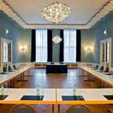 A conference room with a U-shaped table arrangement is set up for a meeting, featuring water bottles and notepads.