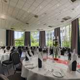 A spacious banquet hall is elegantly set up with round tables and white tablecloths, ready for a festive gathering.