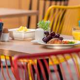 A colorful breakfast spread features croissants, grapes, eggs, and orange juice on a vibrant table setting.