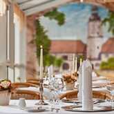 Elegant restaurant table set with candles and floral decor, overlooking a mural of a picturesque tower and landscape.