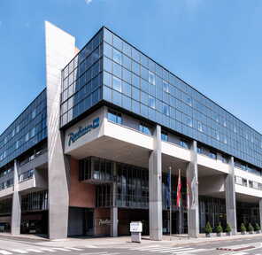 Modern Radisson Blu hotel features sleek architecture and large windows under a clear blue sky. | © Radisson Hotels