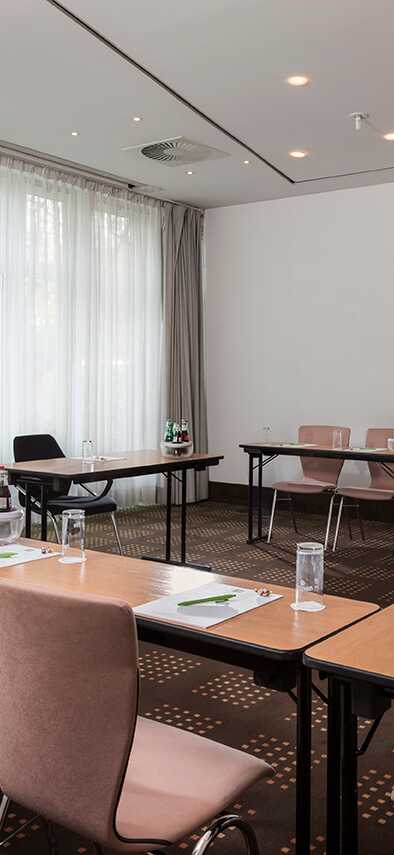 A modern meeting room is set up with tables, chairs, and notepads, ready for a conference or business gathering.