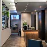 A modern reception area features a sleek desk with plants and a TV screen, creating a welcoming atmosphere.