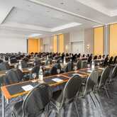 A spacious conference room is set up with neatly arranged tables and chairs, ready for a seminar or meeting.