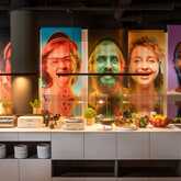 A vibrant breakfast buffet is set in front of colorful portraits, creating a lively atmosphere in the restaurant.